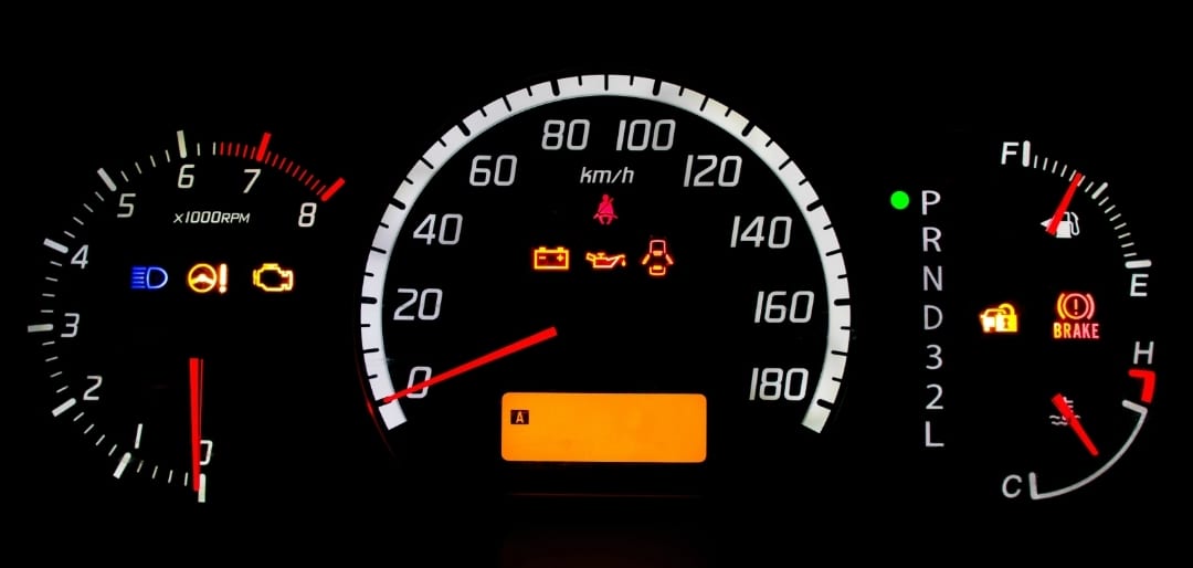 A close up of an instrument cluster with the engine light lit